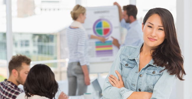 Woman smiling at camera while her colleagues are working