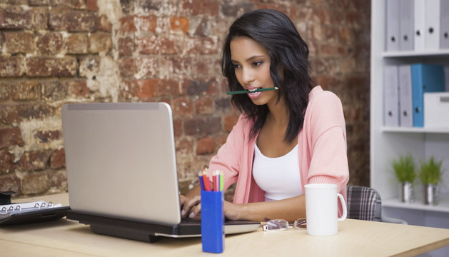 Woman sitting and holding a pencil in her mouth