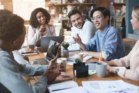 People sitting around a conference table talking and smiling